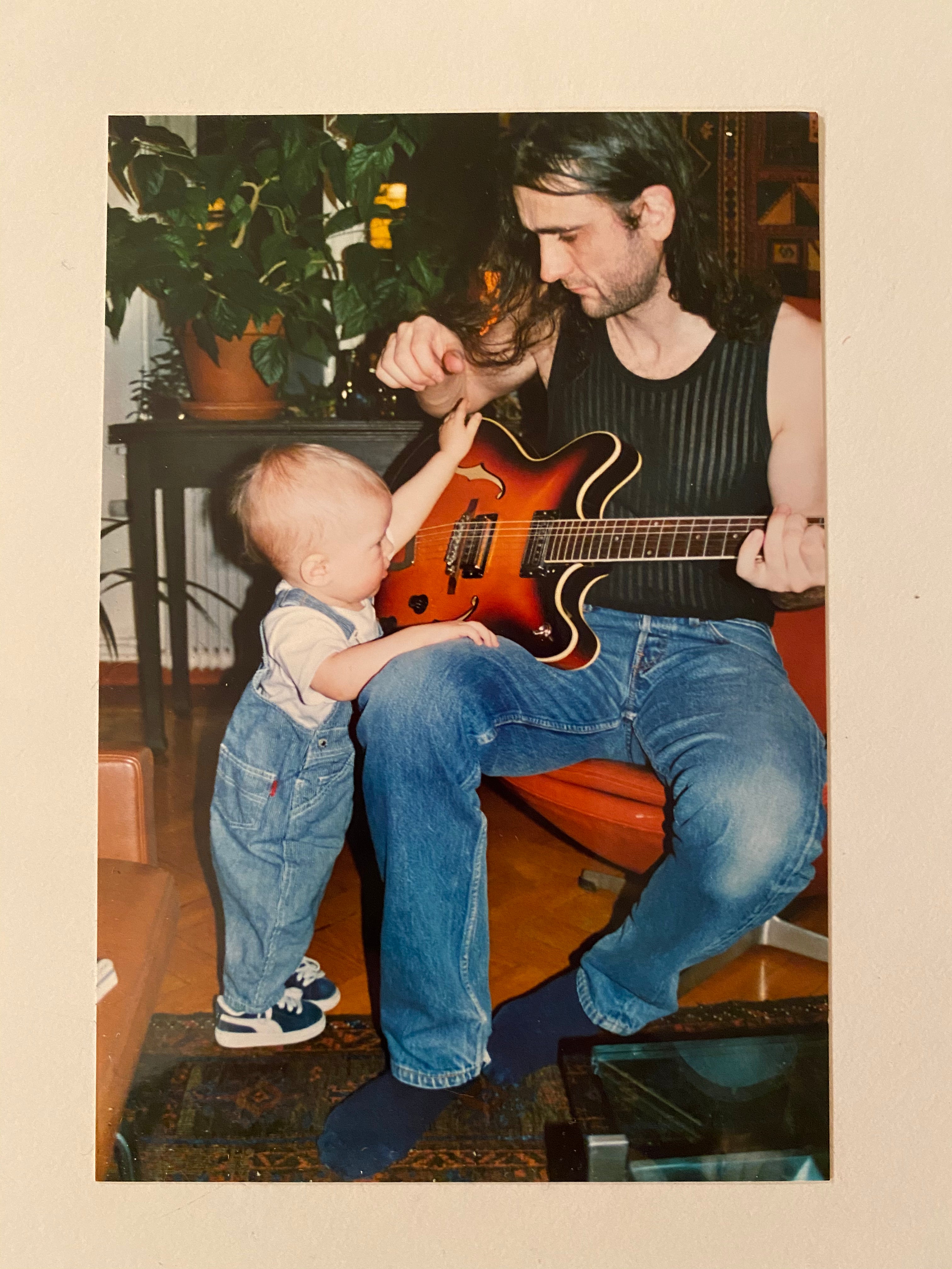 Man playing guitar with a child in a home setting